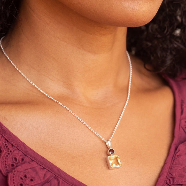 Close-up of woman wearing a square citrine & oval garnet pendant necklace set in sterling silver