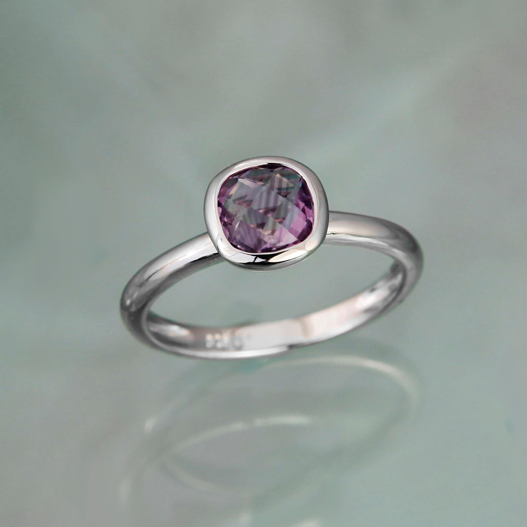 Square amethyst gemstone set on a silver band on a gray background