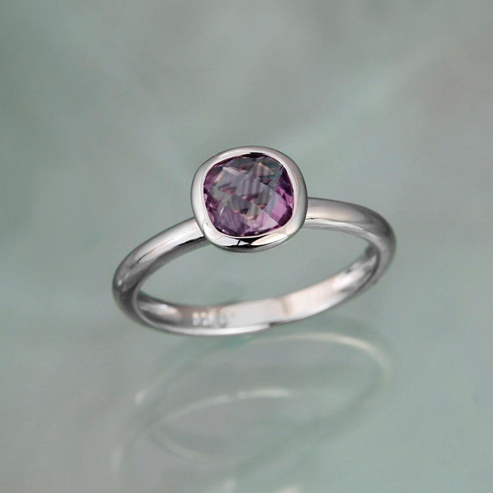 Square amethyst gemstone set on a silver band on a gray background