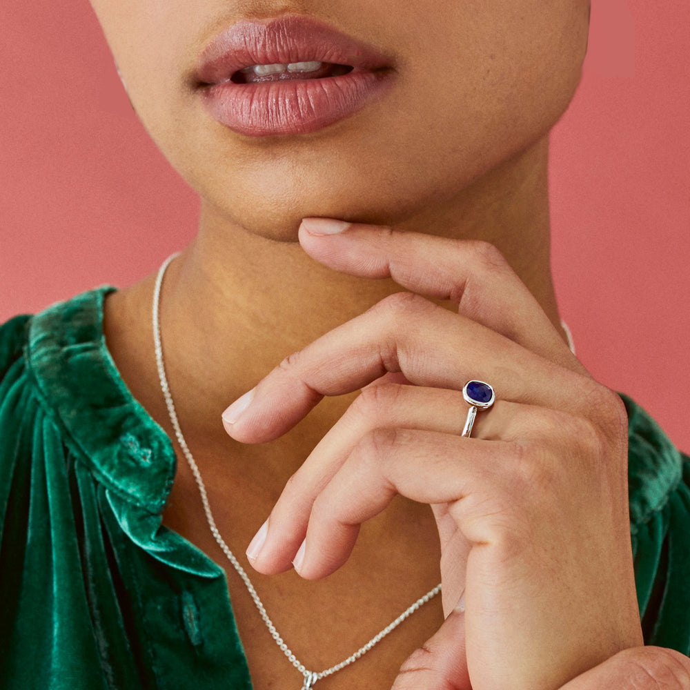 Model wearing a silver and lapis lazuli stone ring with a green top