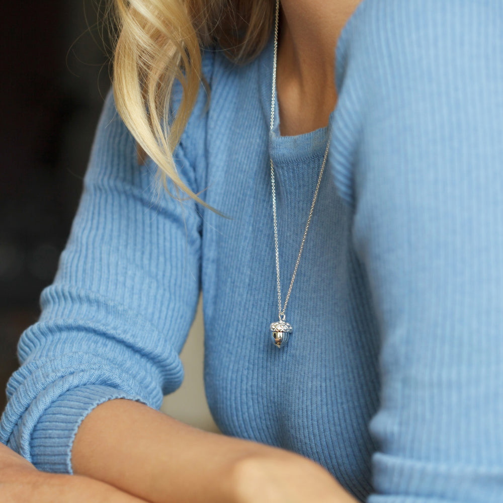 Close-up of woman wearing a sterling silver acorn locket birthstone pendant necklace