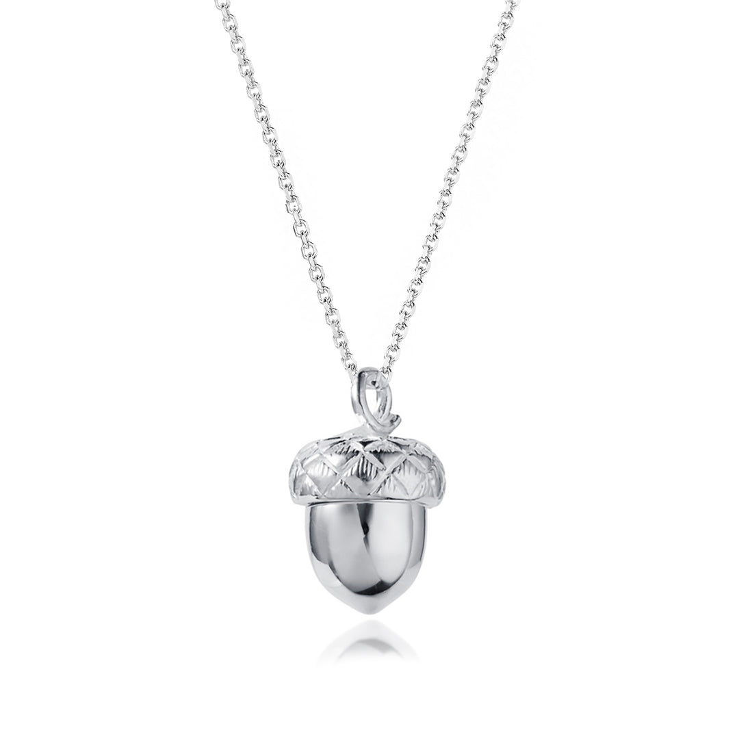 Closed silver acorn locket necklace on white background.