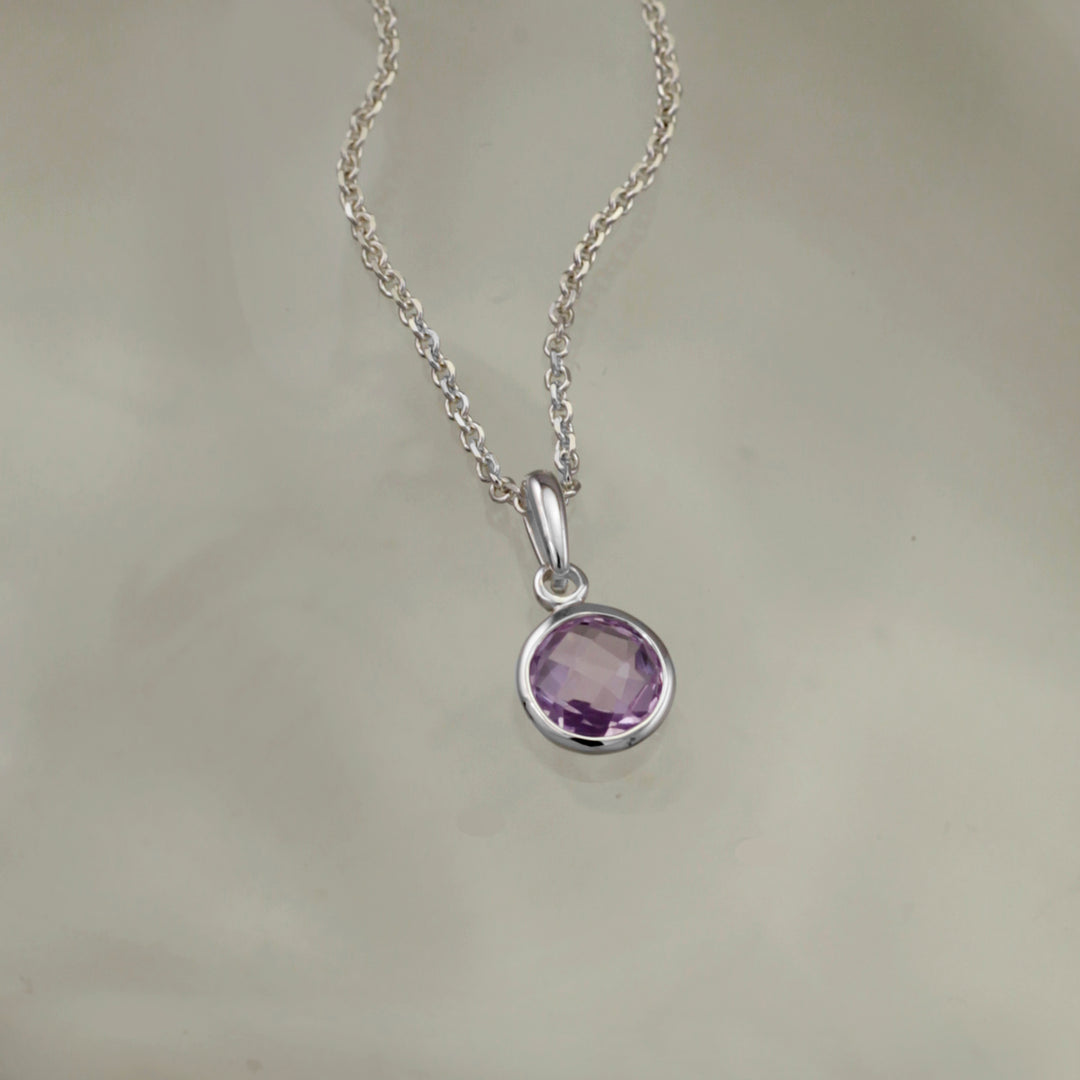 Silver pendant with amethyst on a gray background
