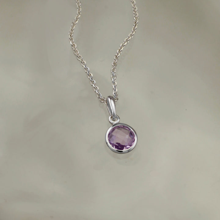 Silver pendant with amethyst on a gray background