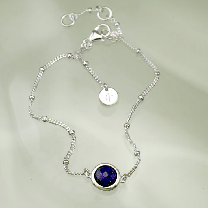Sterling silver beaded chain bracelet with lapis lazuli on a reflective background