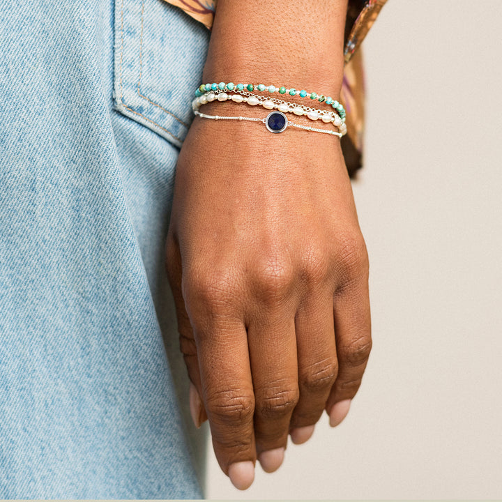 Woman wearing a sterling silver beaded chain bracelet with lapis lazuli as part of  a bracelet stack