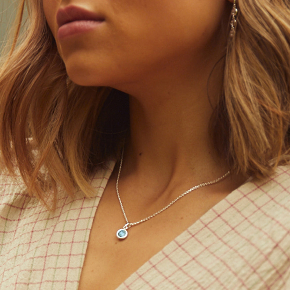 Close-up of model wearing a silver and blue topaz pendant necklace