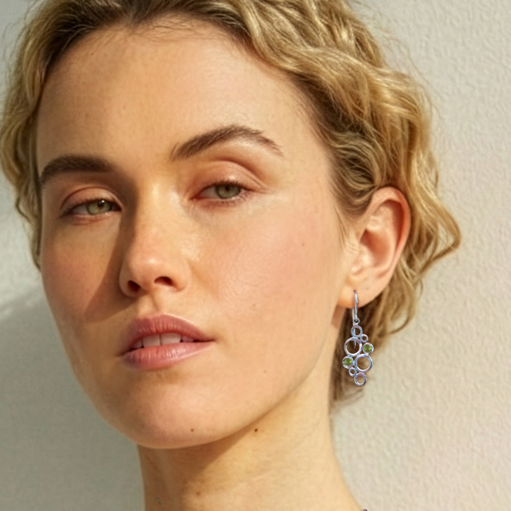 Woman wearing Sterling silver geometric drop earrings with green peridot cabochon gemstones