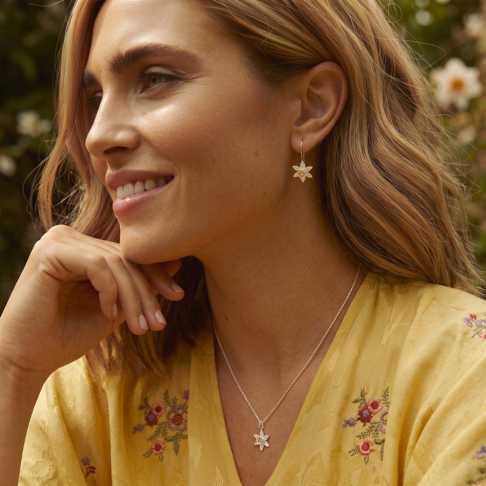 Woman wearing sterling silver daffodil flower threader earring and necklace set with gold details