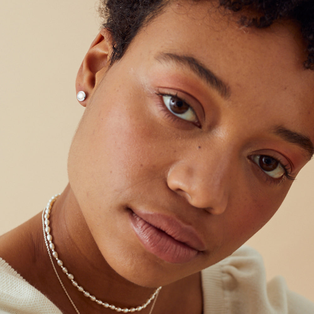 Model wearing dainty silver and moonstone post earrings
