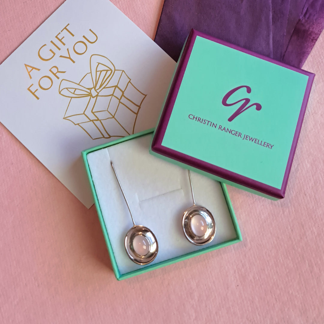 Sterling silver long dish drop earrings with an oval rose quartz cabochon gemstone in Christin Ranger Jewellery gift packaging