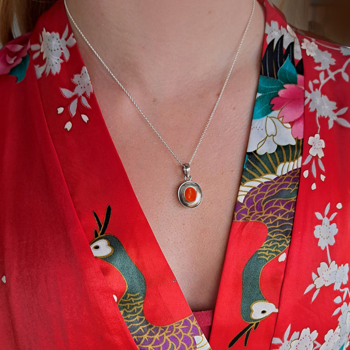Model wearing a sterling silver dish pendant with carnelian cabochon gemstone
