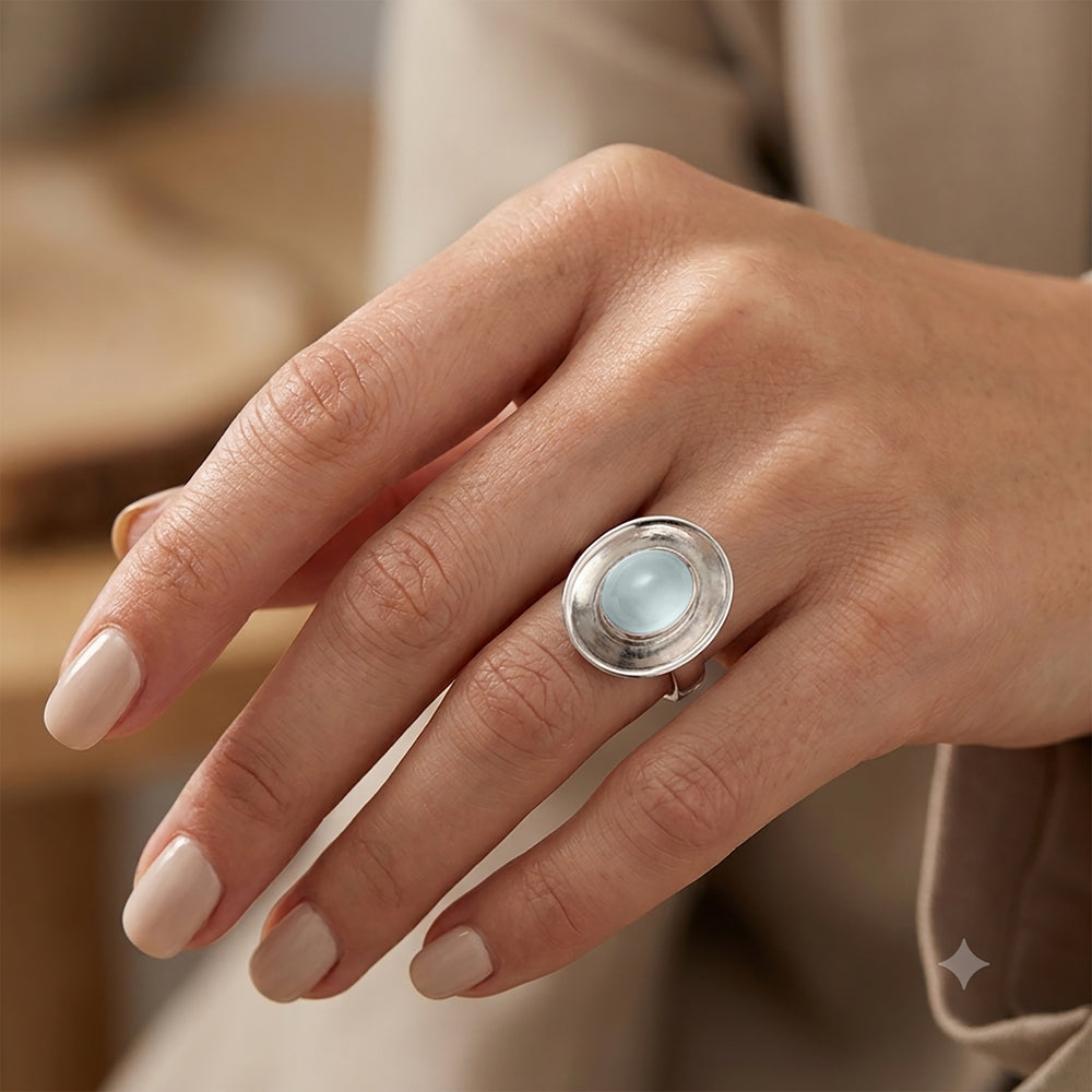Woman wearing a sterling silver dish shaped ring with aquamarine cabochon gemstone