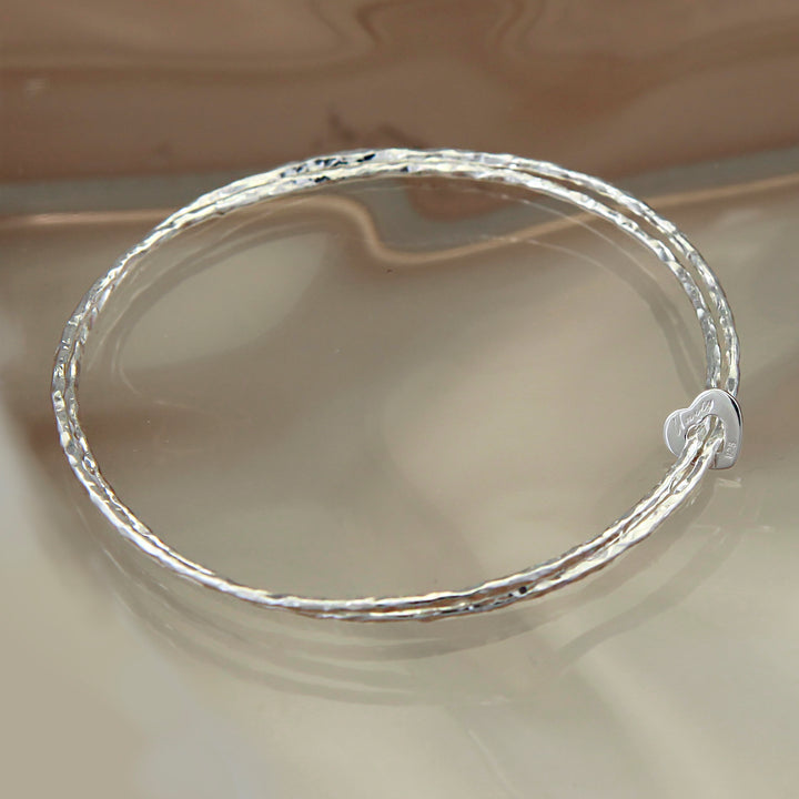 Sterling silver heart eternity double bangle on a reflective background
