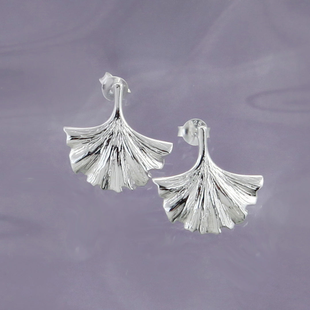 Silver gingko leaf-shaped earrings on a purple background