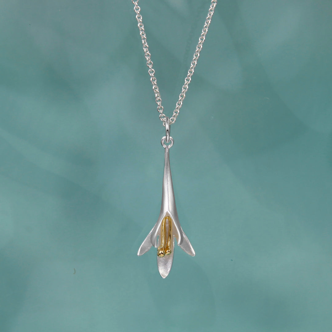Sterling silver and gold vermeil long fuchsia flower pendant necklace on a teal background