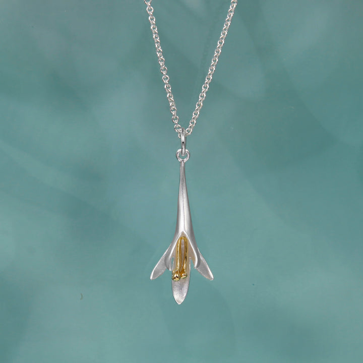 Sterling silver and gold vermeil long fuchsia flower pendant necklace on a teal background