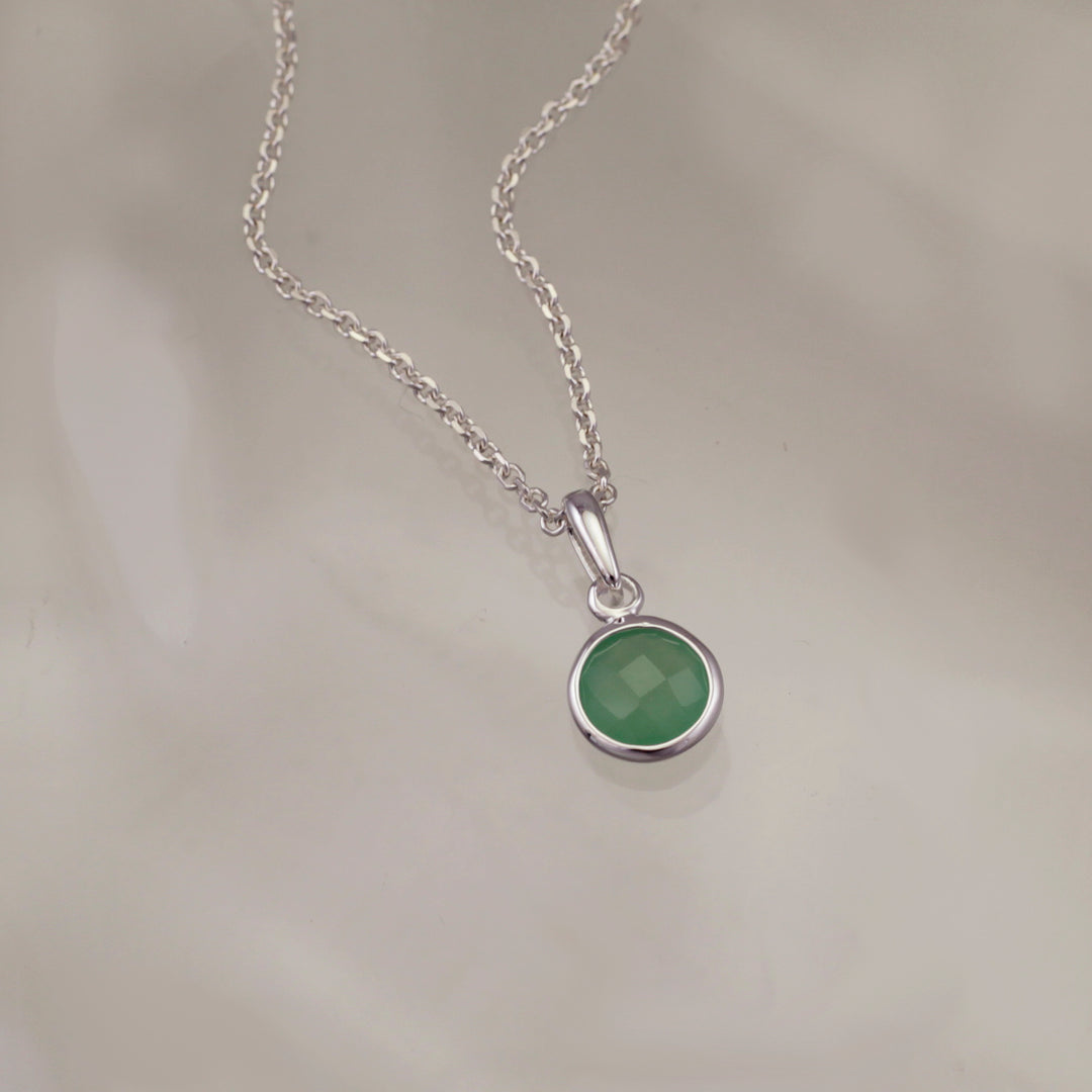 Green quartz and silver pendant necklace on a gray background