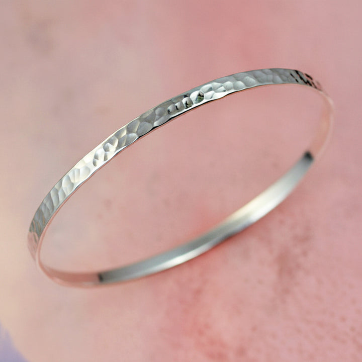 Sterling Silver Hammered Bangle on a pink background