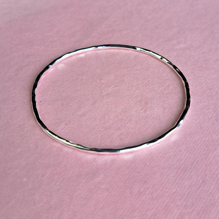 Sterling silver hoola hoop bangle on a pink background