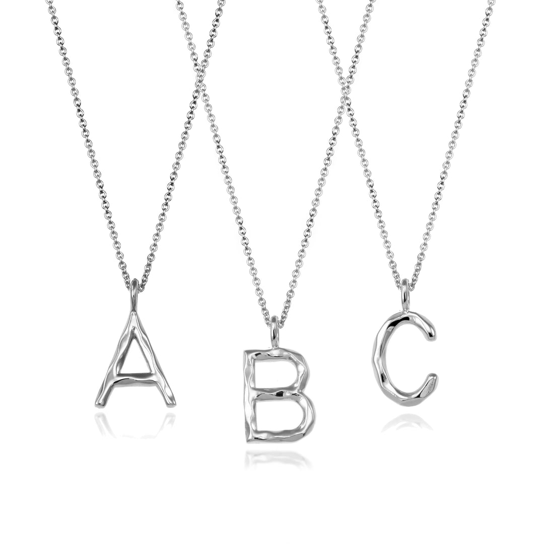 Three silver initial necklaces on a white background