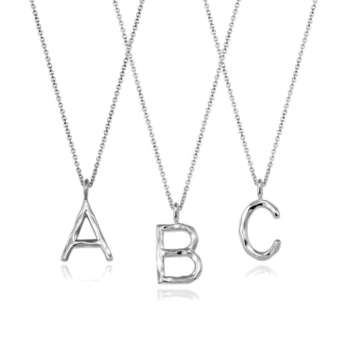 Three silver initial necklaces on a white background