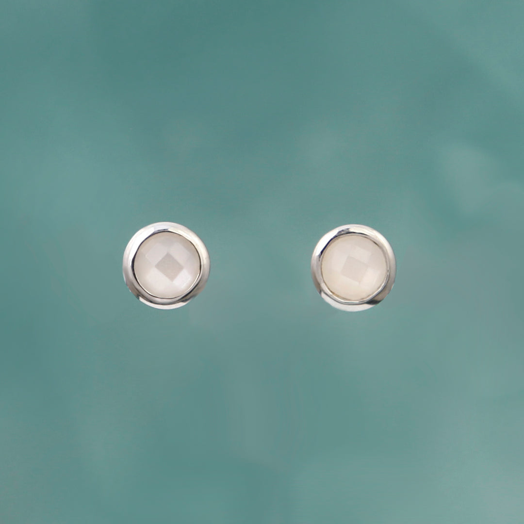 Moonstone and silver stud earrings on an aqua background