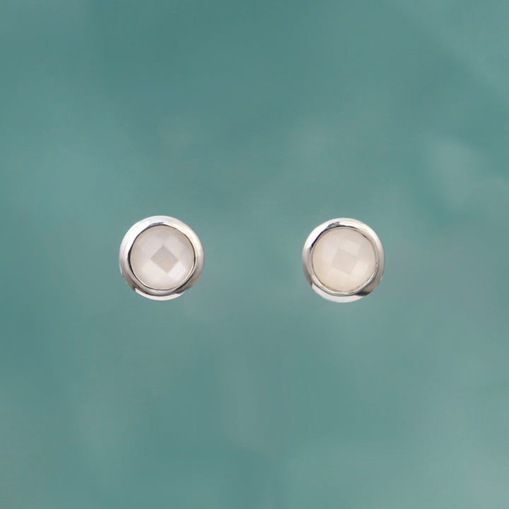Moonstone and silver stud earrings on an aqua background
