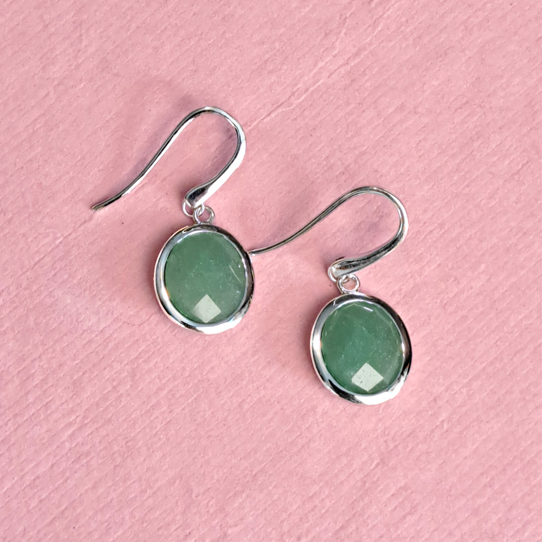 Sterling silver oval drop earrings with jade-green aventurine on a pink background