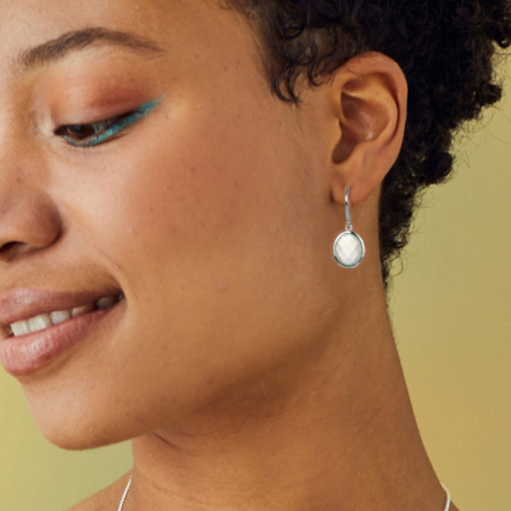Close-up of woman wearing sterling silver oval white moonstone drop earrings
