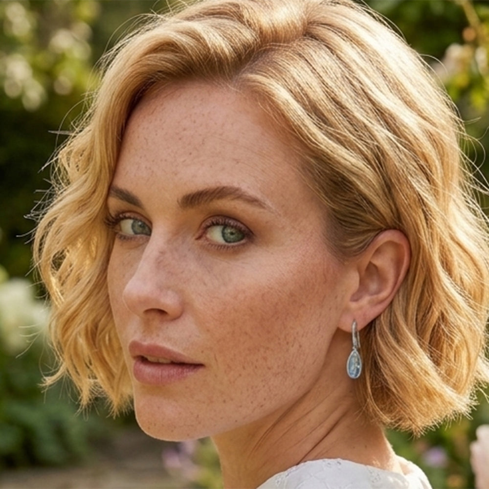 Woman wearing Sterling silver pear drop earrings with blue topaz