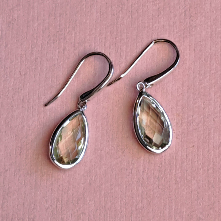 Sterling silver pear drop earrings with green amethyst on a pink paper background