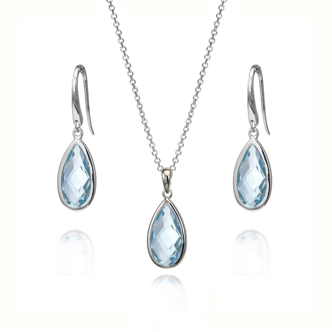 Silver jewelry set featuring a teardrop-shaped light blue gemstone pendant necklace, matching drop earrings, and a delicate chain on a white background.