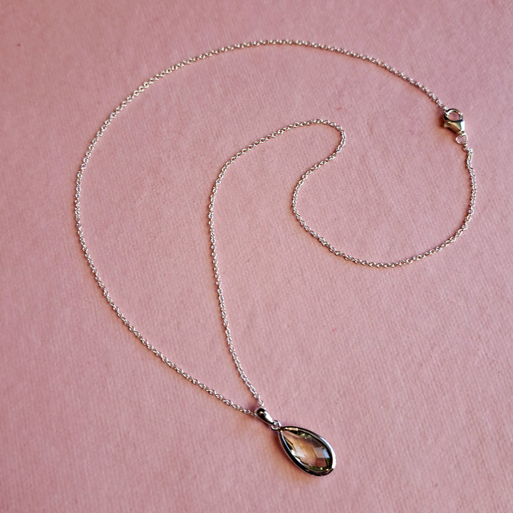 Sterling silver pear drop pendant necklace in green amethyst on a pink background