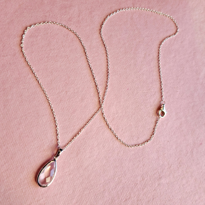 Sterling silver pear drop pendant necklace with rose quartz against a pink background