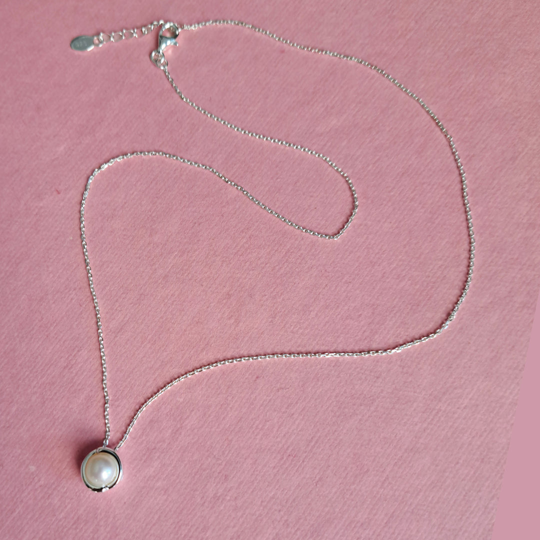 Sterling silver pearl pendant necklace on a pink background