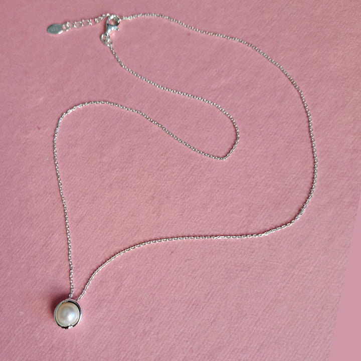 Sterling silver pearl pendant necklace on a pink background