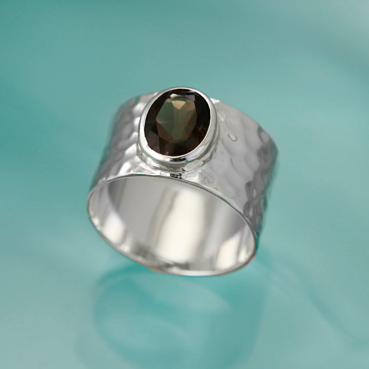 Sterling silver wide band ring with natural smoky quartz gemstone on an aqua background