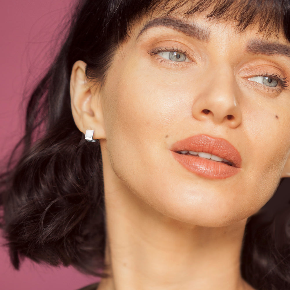 Close-up of woman wearing silver huggie hoop earrings