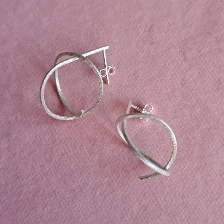 Sterling silver spiral stud earrings alternative view on a pink background