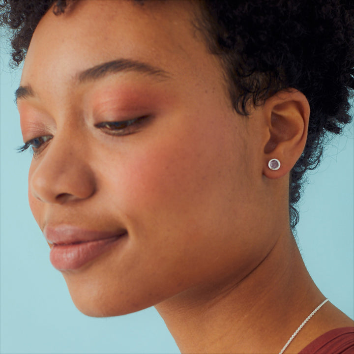 Close-up of a woman wearing sterling silver amethyst stud earrings