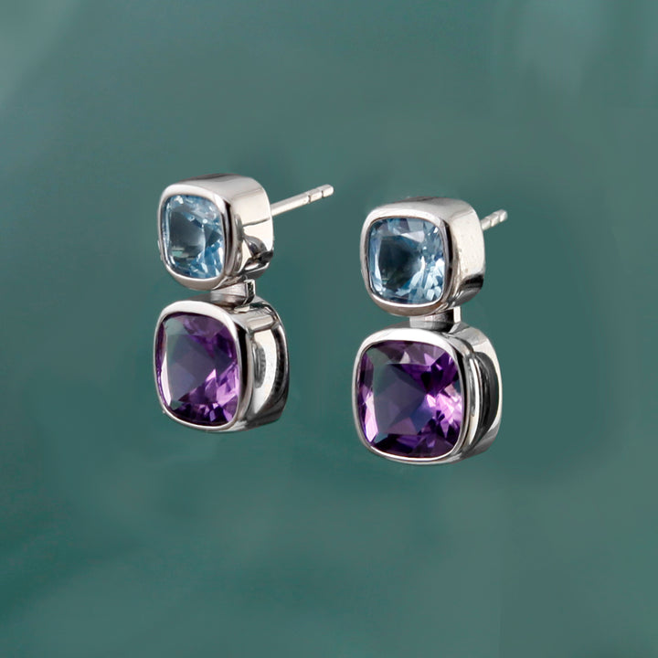 Sterling silver amethyst and blue topaz stud earrings on an aqua background