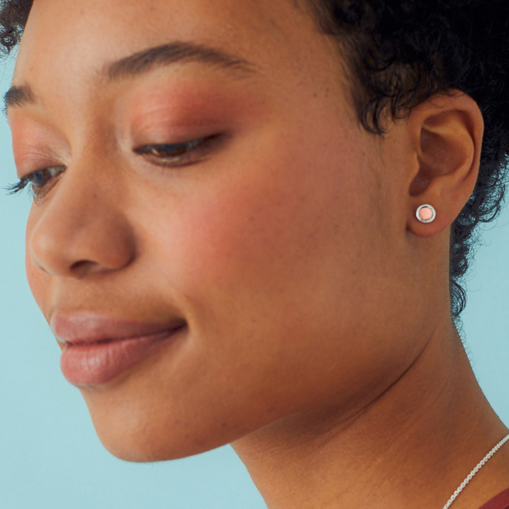 Close-up of woman wearing sterling silver stud earrings set with pink opal 