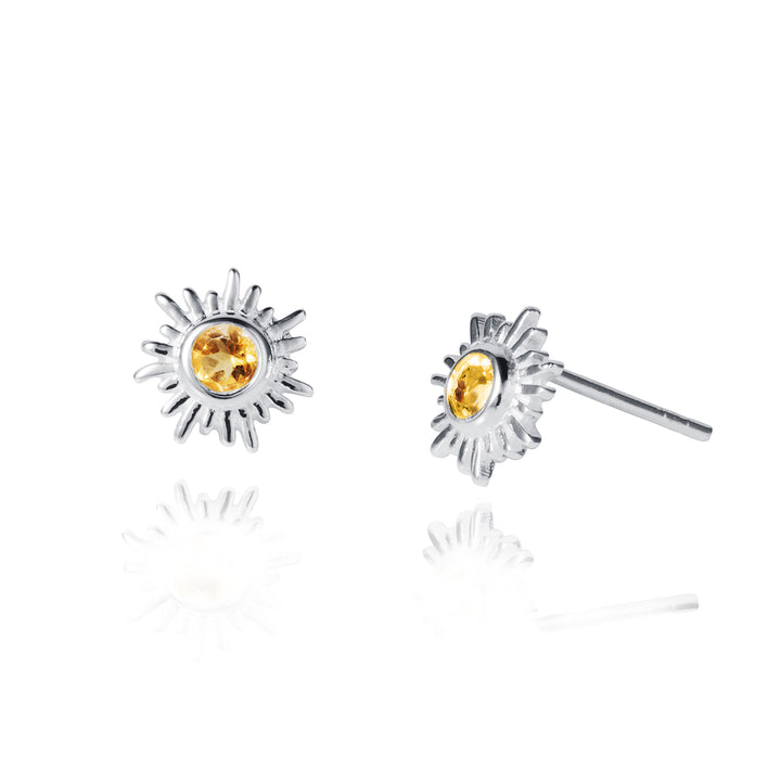 Silver sun-shaped earrings with yellow gemstones on a white background