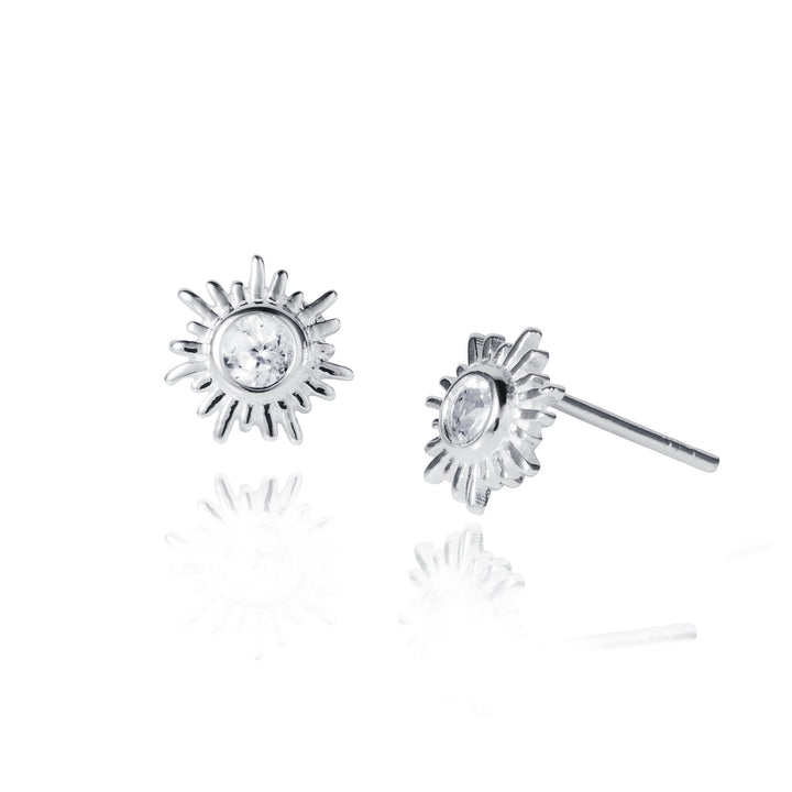 Silver sun-shaped earrings with clear gemstones on a white background
