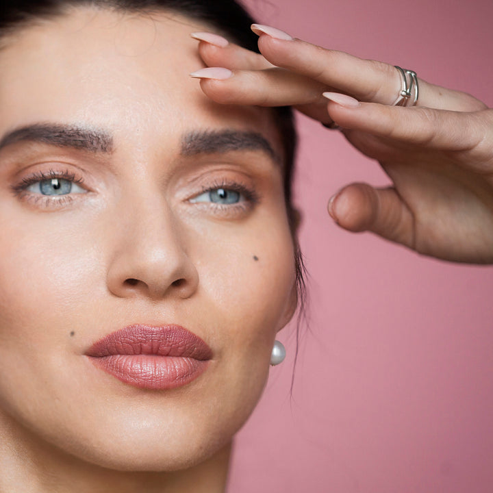 Model wearing a silver ring with a knot design with pink background