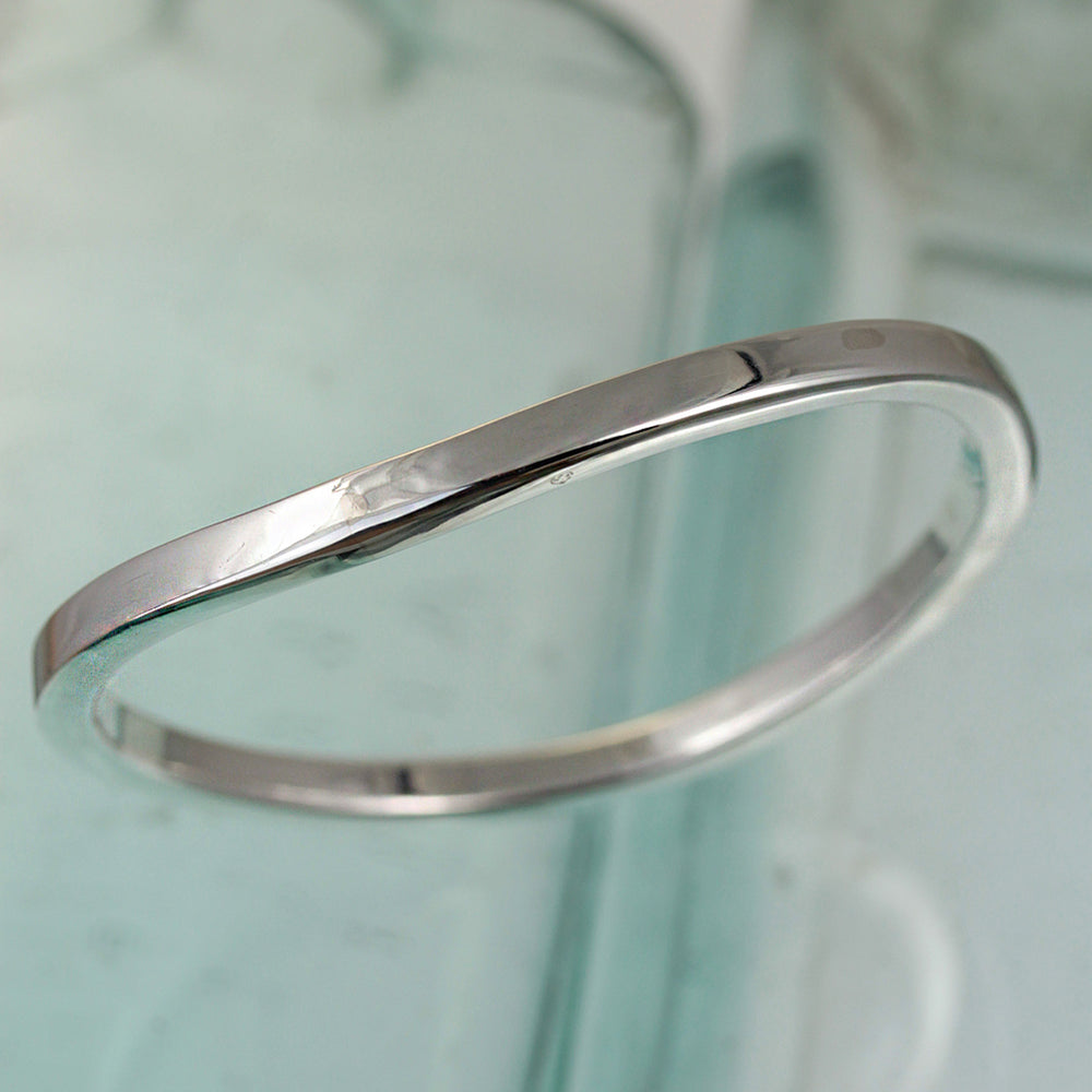Sterling silver wave bangle in square tubing on a reflactive background