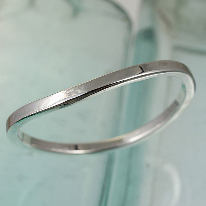 Sterling silver wave bangle in square tubing on a reflactive background