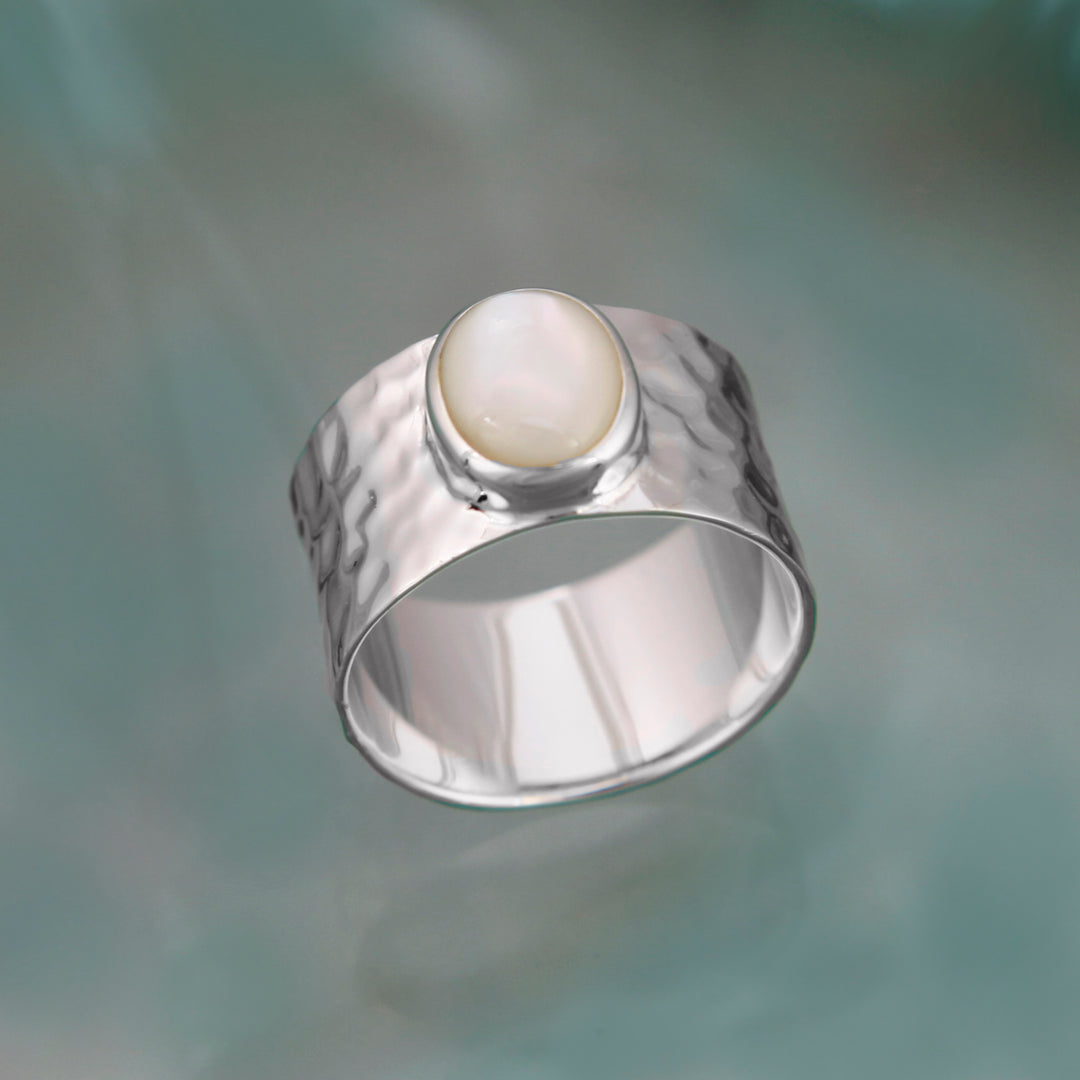 Sterling silver wide band ring with mother-of-pearl on a coloured background