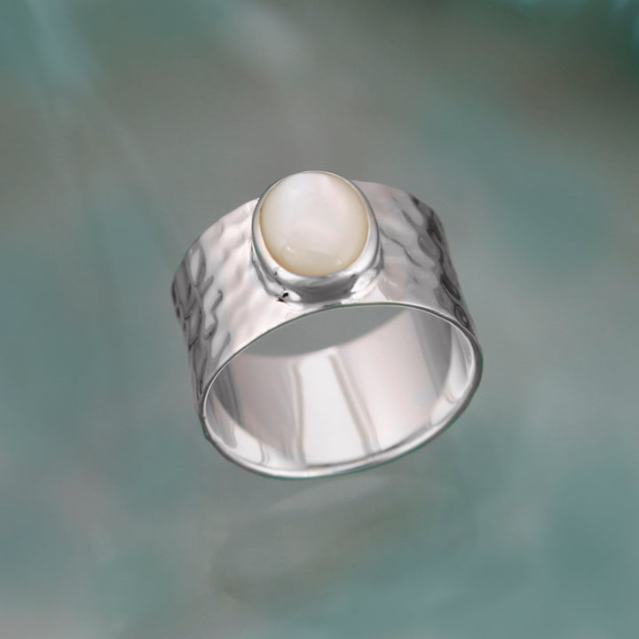 Sterling silver wide band ring with mother-of-pearl on a coloured background